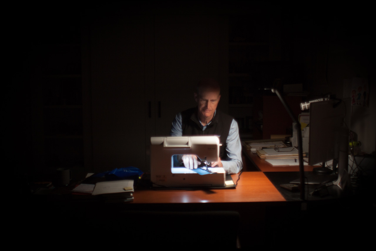 Glen Van Peski sewing gear at his desk late at night