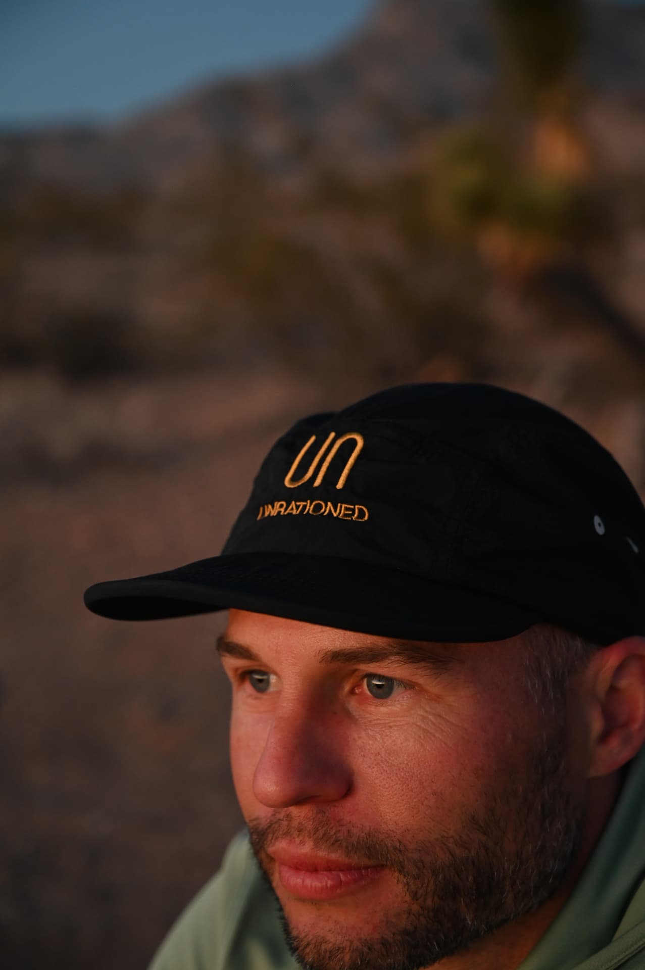 A man in an Unrationed cap looking out over the desert at last light